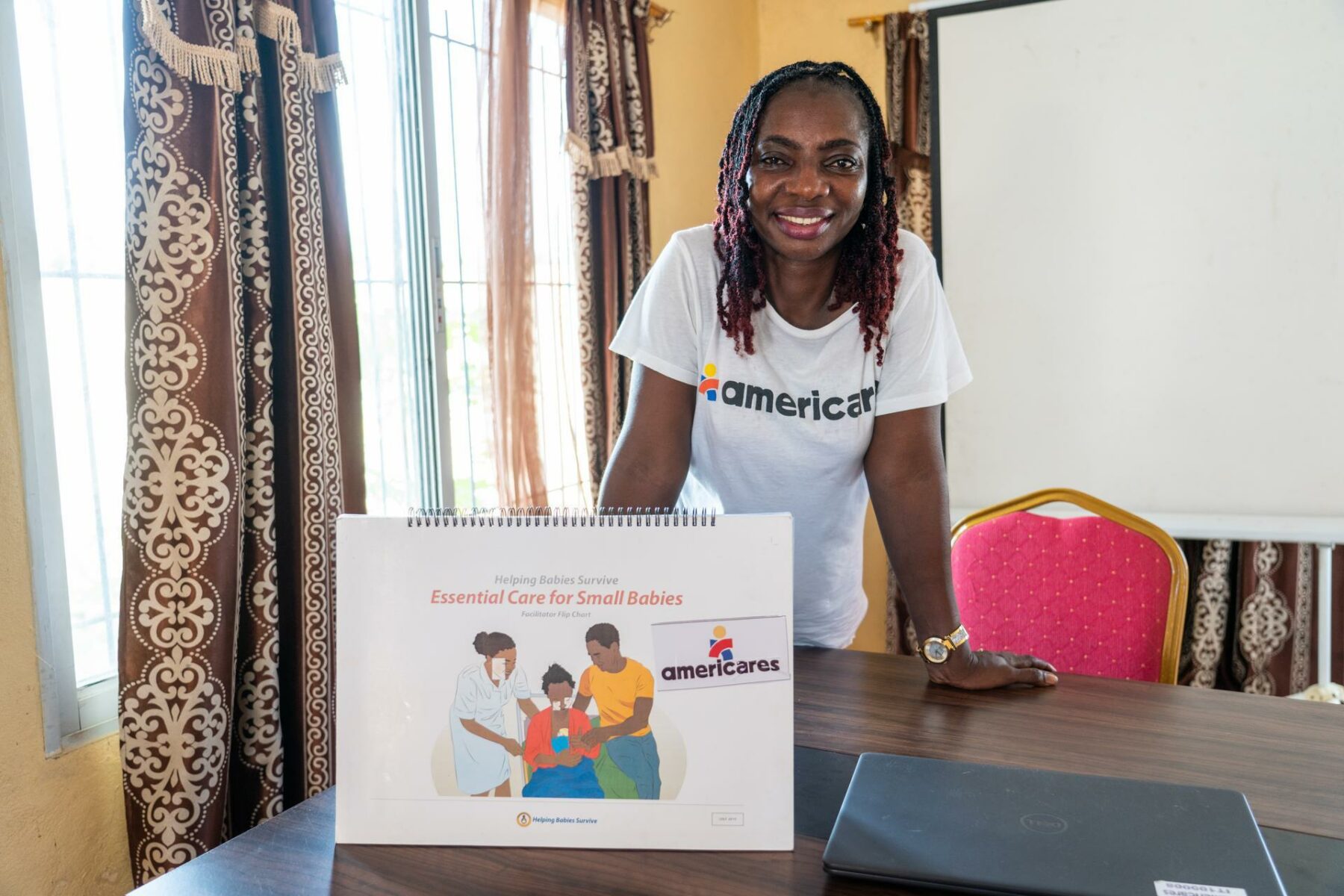 Americares Senior Officer Damawah Saye leans over table, ready to train midwives.