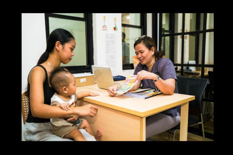 A health worker at the Mabitac Rural Health Unit shares toolkit resources with a patient. Photo by Peter Carney/Americares